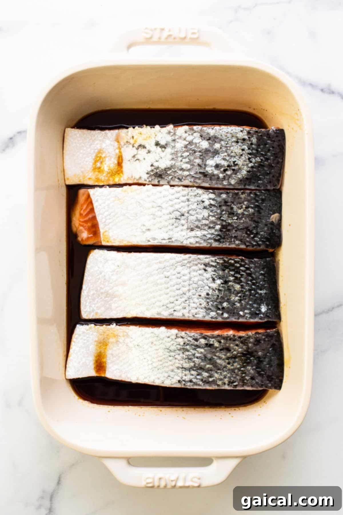 This yummy honey glazed salmon comes our caramelized and flakey. It's made with honey, soy sauce, and fresh ginger! Raw salmon fillets marinating in a clear glass dish, soaking up the honey ginger soy glaze.