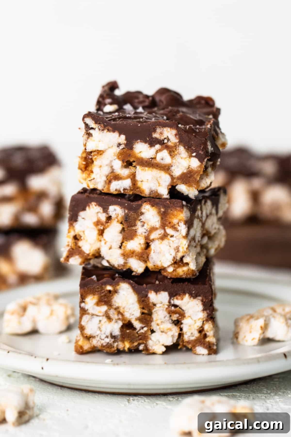 Rice Cake Dream Bars 5 A stack of perfectly cut, chocolate-topped bars on a rustic wooden plate, ready for serving.