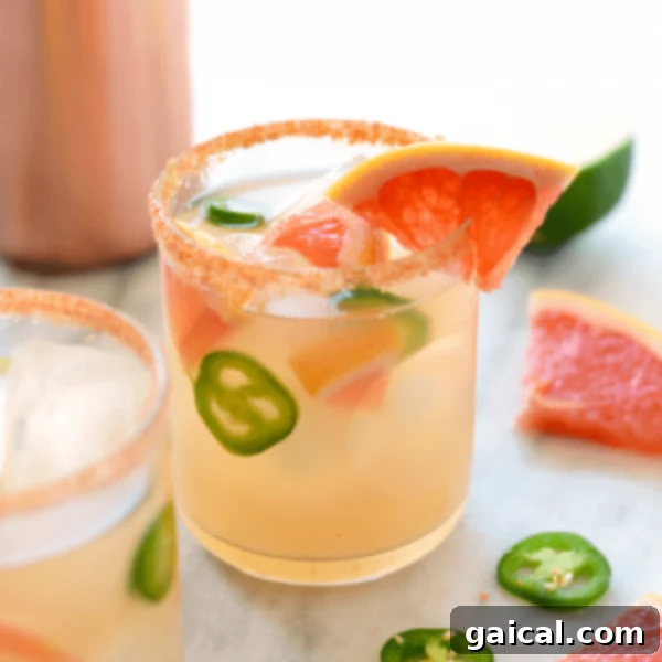 Two glasses of grapefruit margarita with jalapeños and limes.