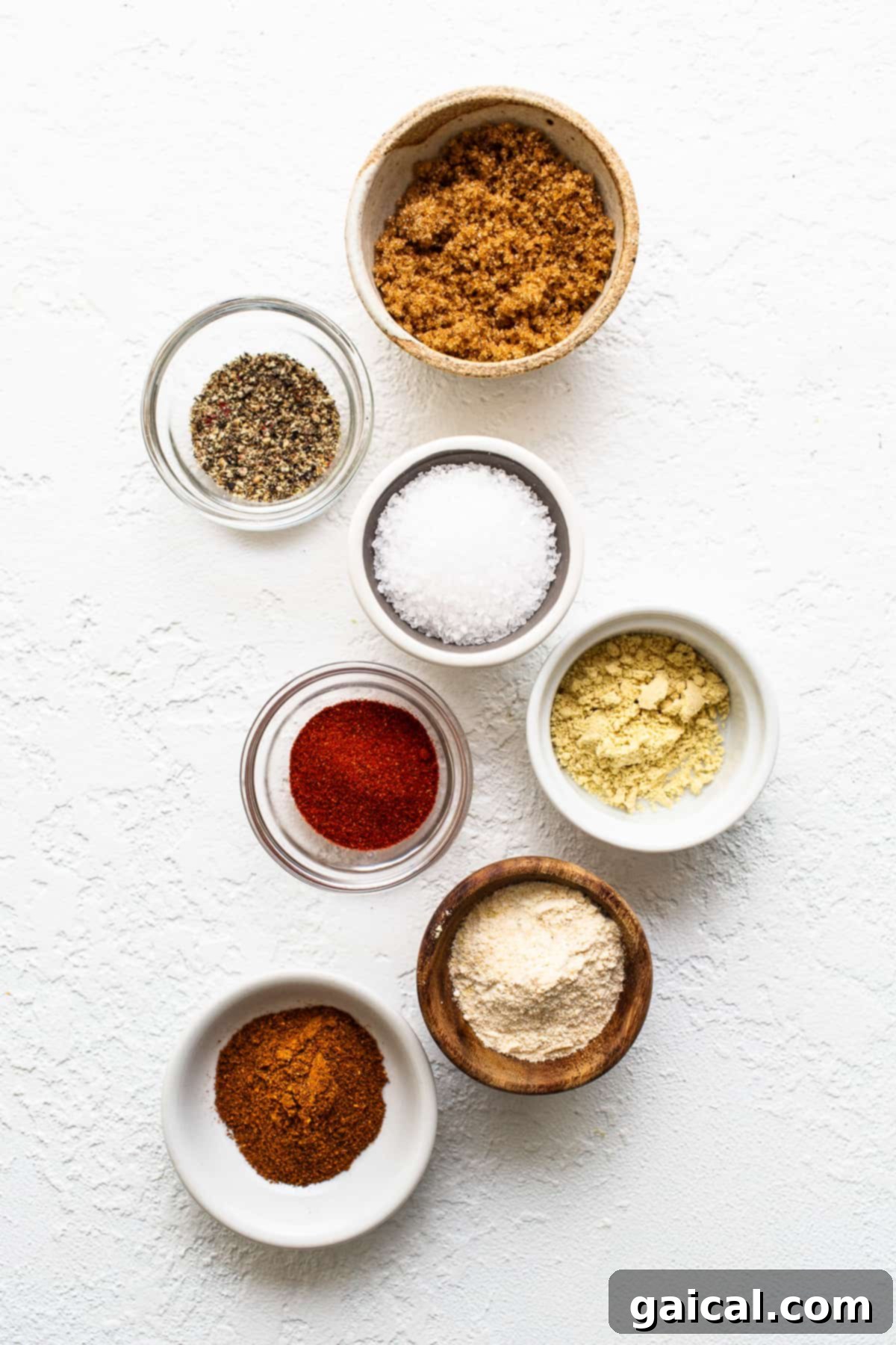 A selection of dry rub ingredients for smoked pork shoulder laid out on a surface.