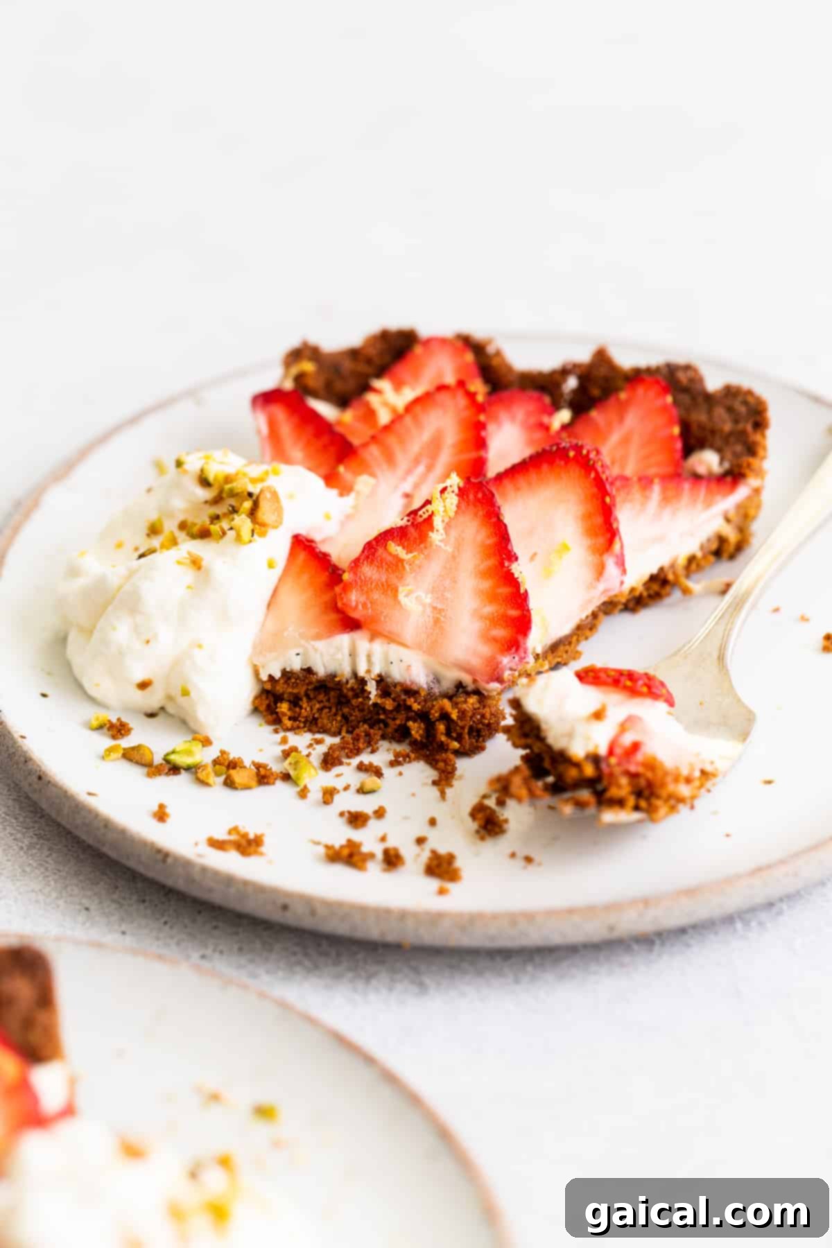 Pistachio-Crusted Strawberry Delight 7 The full strawberry tart on a white cake stand, surrounded by loose strawberries and mint.