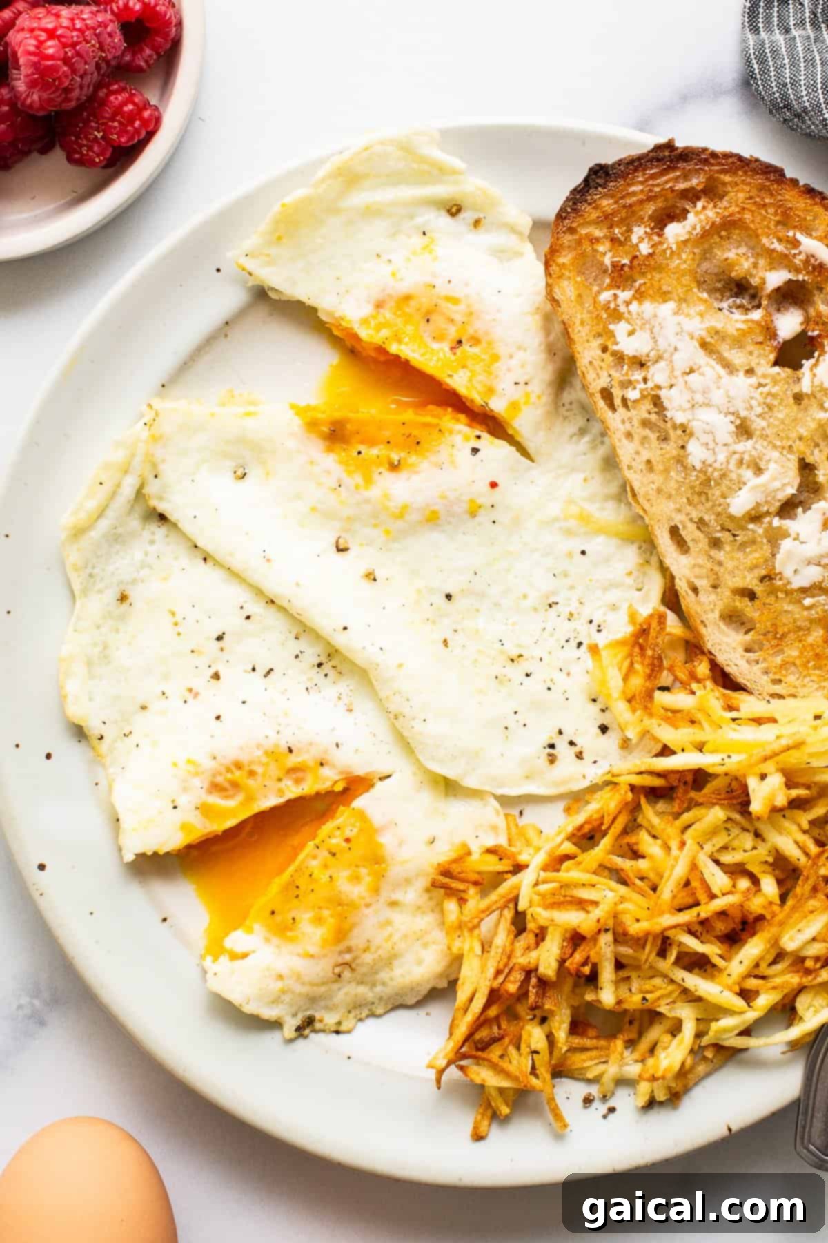 Over medium eggs on a plate with toast and hot sauce, ready to eat.