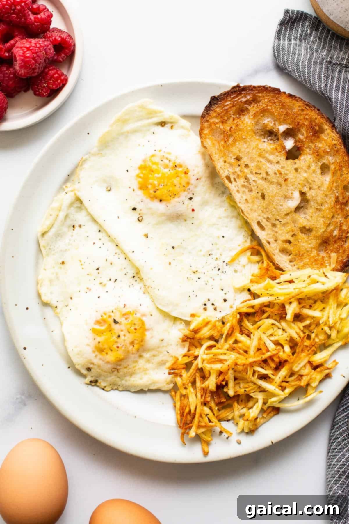 A plate of over medium eggs served with toast, ready to be seasoned.