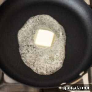 Butter melting in a frying pan on a stove.