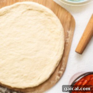 Cast Iron Pizza Oven and Grill 6 rolled out pizza dough on a floured surface.