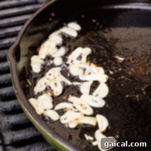 Cast Iron Pizza Oven and Grill 8 garlic cooking in a cast iron pan on a grill.
