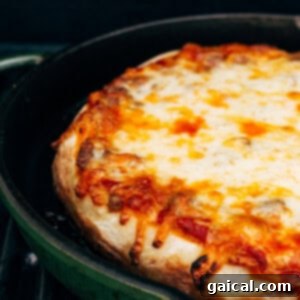 Cast Iron Pizza Oven and Grill 10 pizza cooking on grill in cast iron pan.