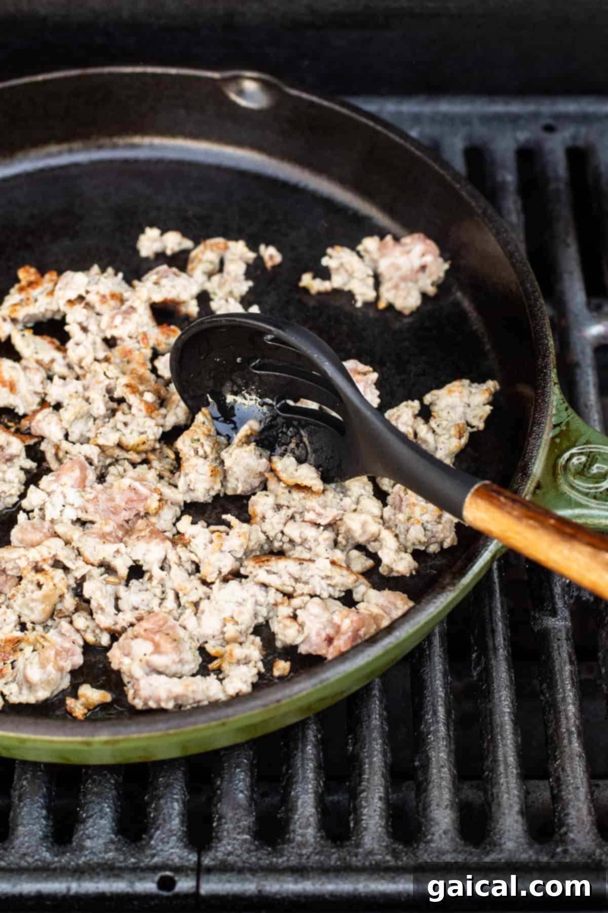 Preparing Sausage for Cast Iron Pizza cooking sausage in cast iron skillet, showing the browning process.