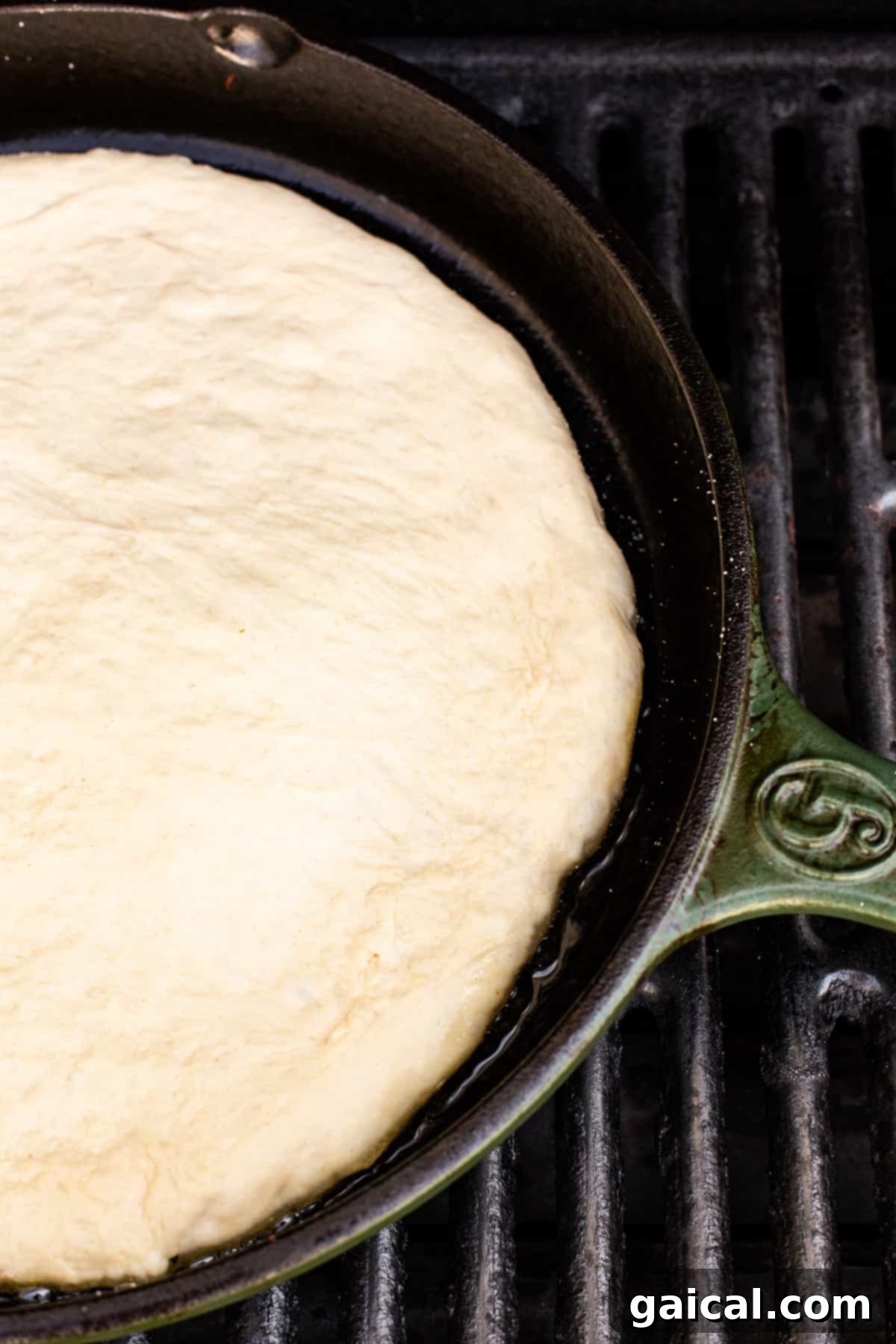 Pre-cooking Pizza Crust on the Grill cooking pizza crust in cast iron skillet on a grill.