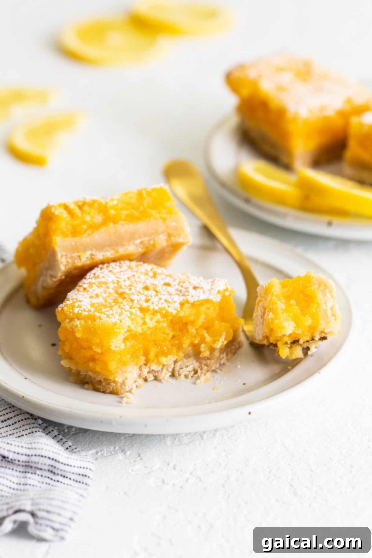 Zesty Lemon Bars 2 Delicious lemon bars presented on a plate with a fork, ready to be enjoyed.