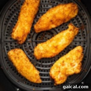 A batch of perfectly air-fried chicken tenders resting in the air fryer basket after cooking.