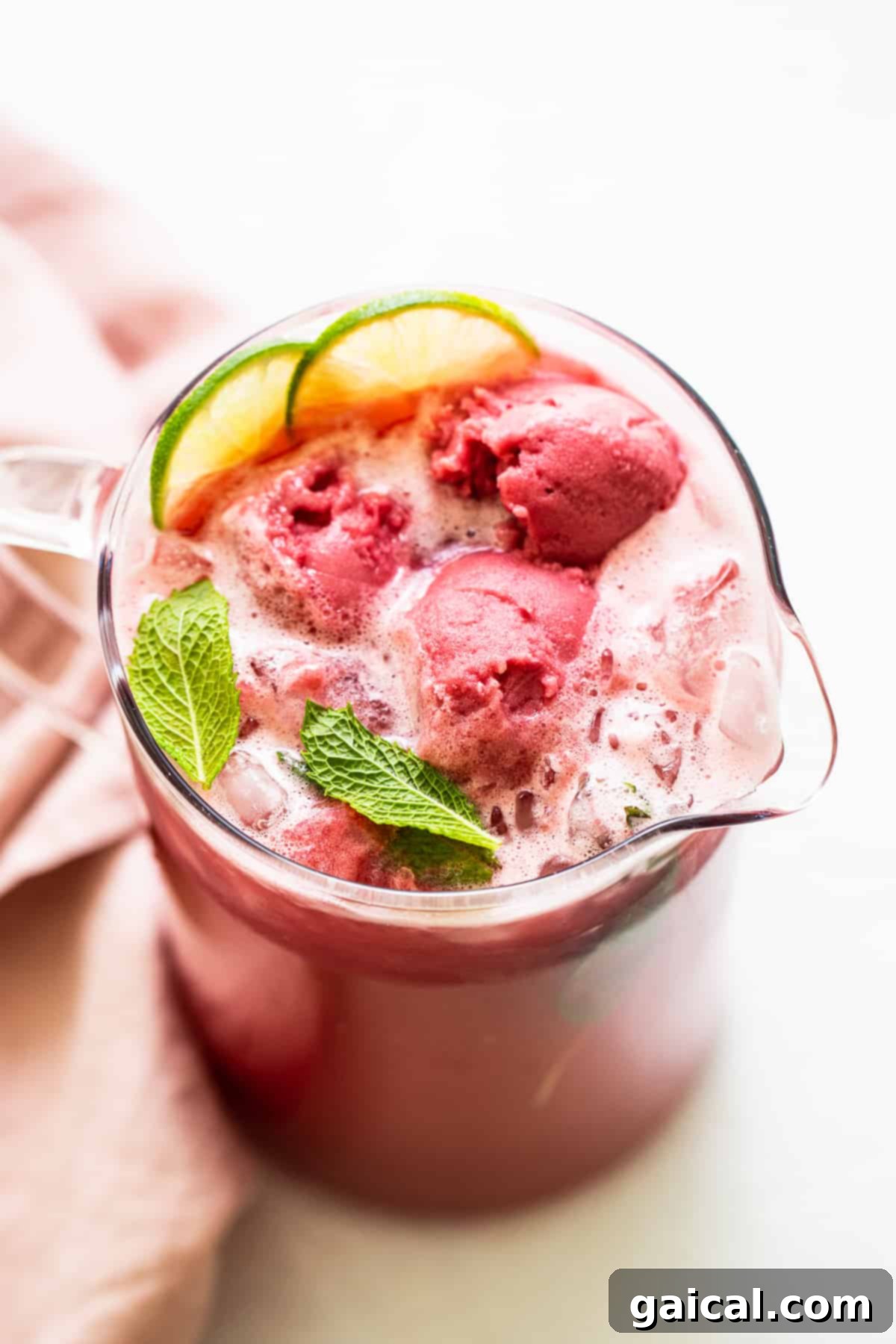 Ultimate Raspberry Vodka Summer Punch: Your Go-To Refreshing Large Batch Cocktail Vibrant raspberry summer punch in an elegant glass pitcher, garnished generously with fresh mint leaves and bright lime slices, promising ultimate refreshment.
