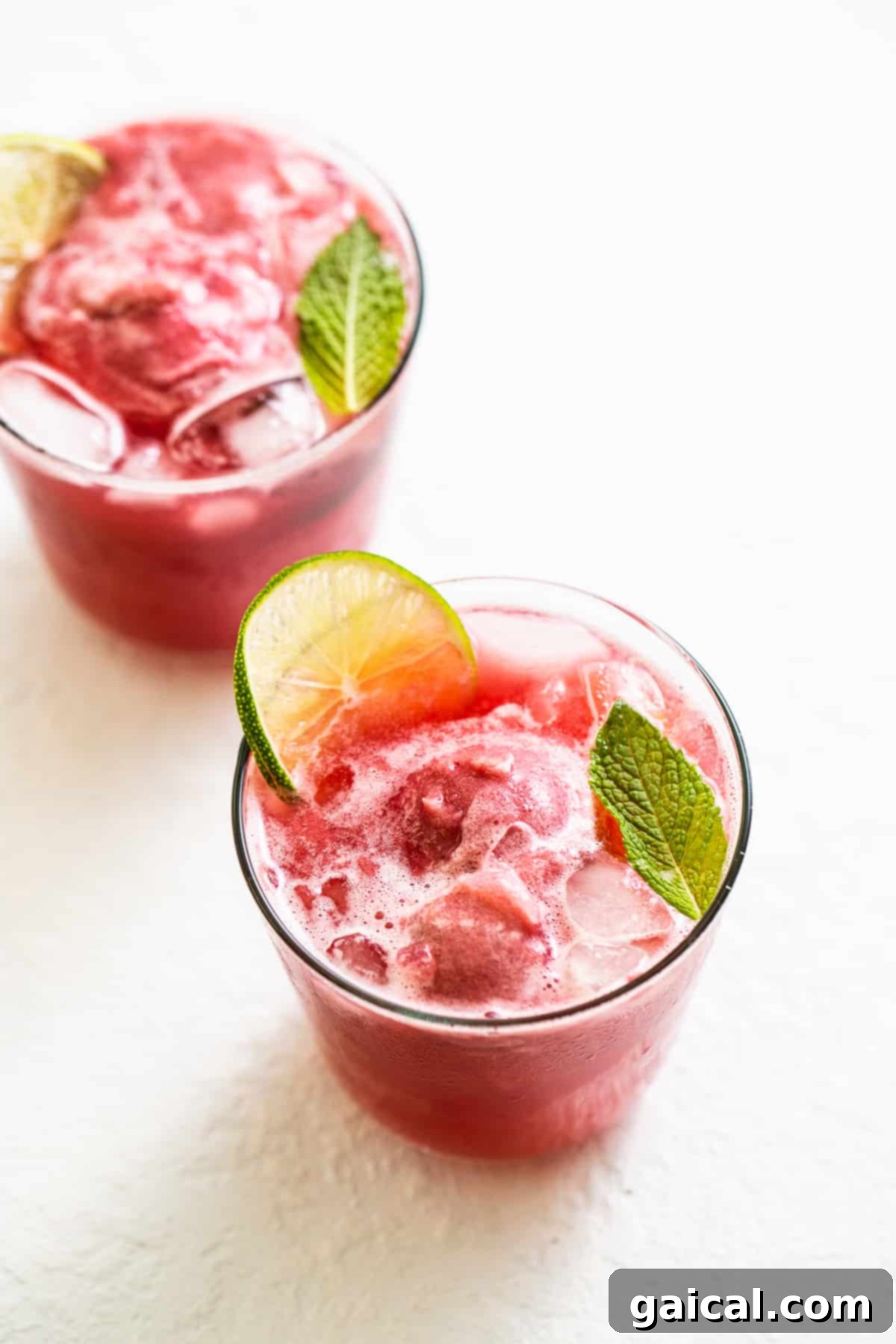 Serve and Enjoy Your Delightful Raspberry Vodka Punch Individual serving glasses elegantly filled with refreshing raspberry vodka punch, each beautifully garnished with fresh mint and berries, inviting guests to enjoy a perfect summer sip.