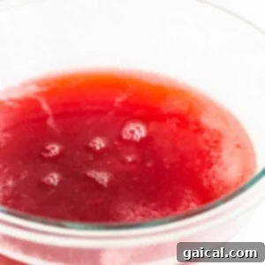 A bowl of freshly strained, bright red raspberry juice, ready to be chilled.