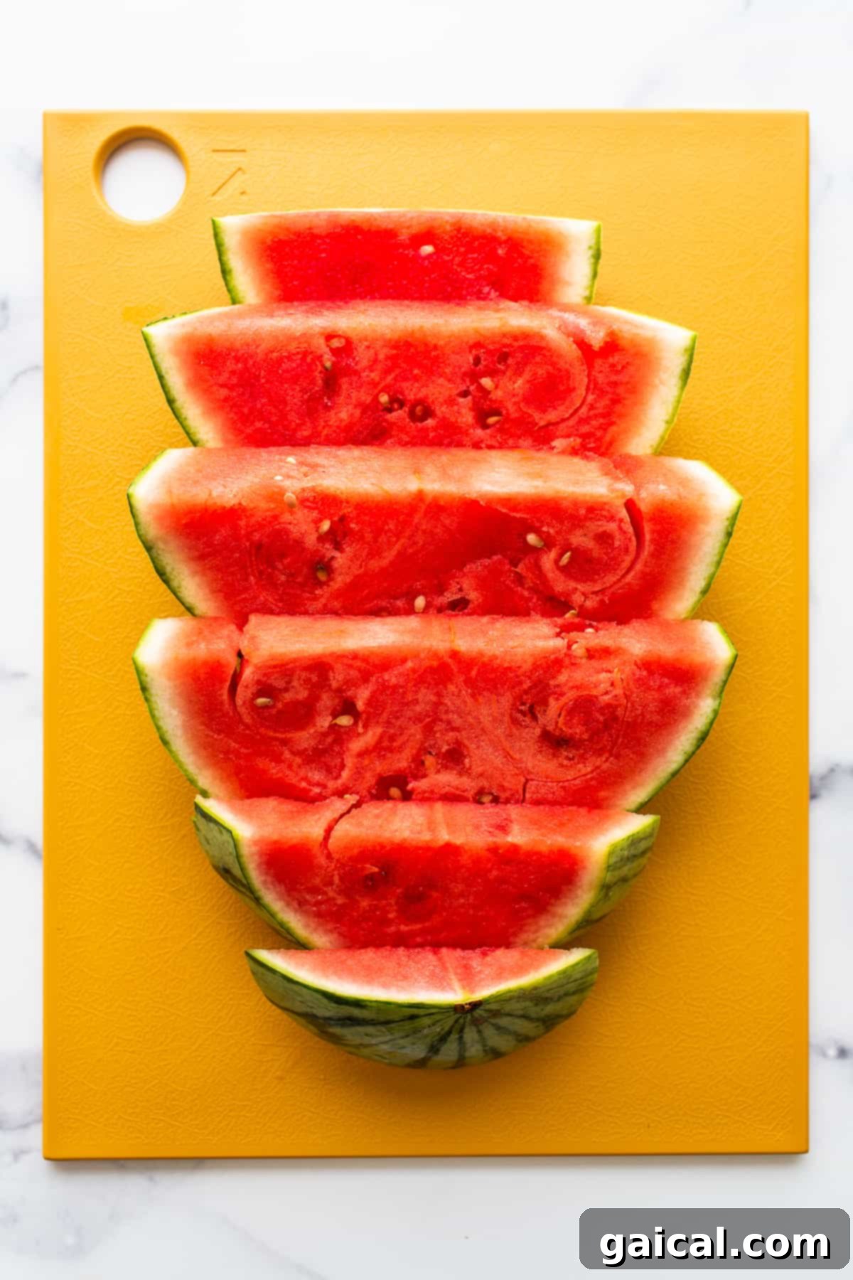 Freshly sliced watermelon on a wooden cutting board, ready for dicing.