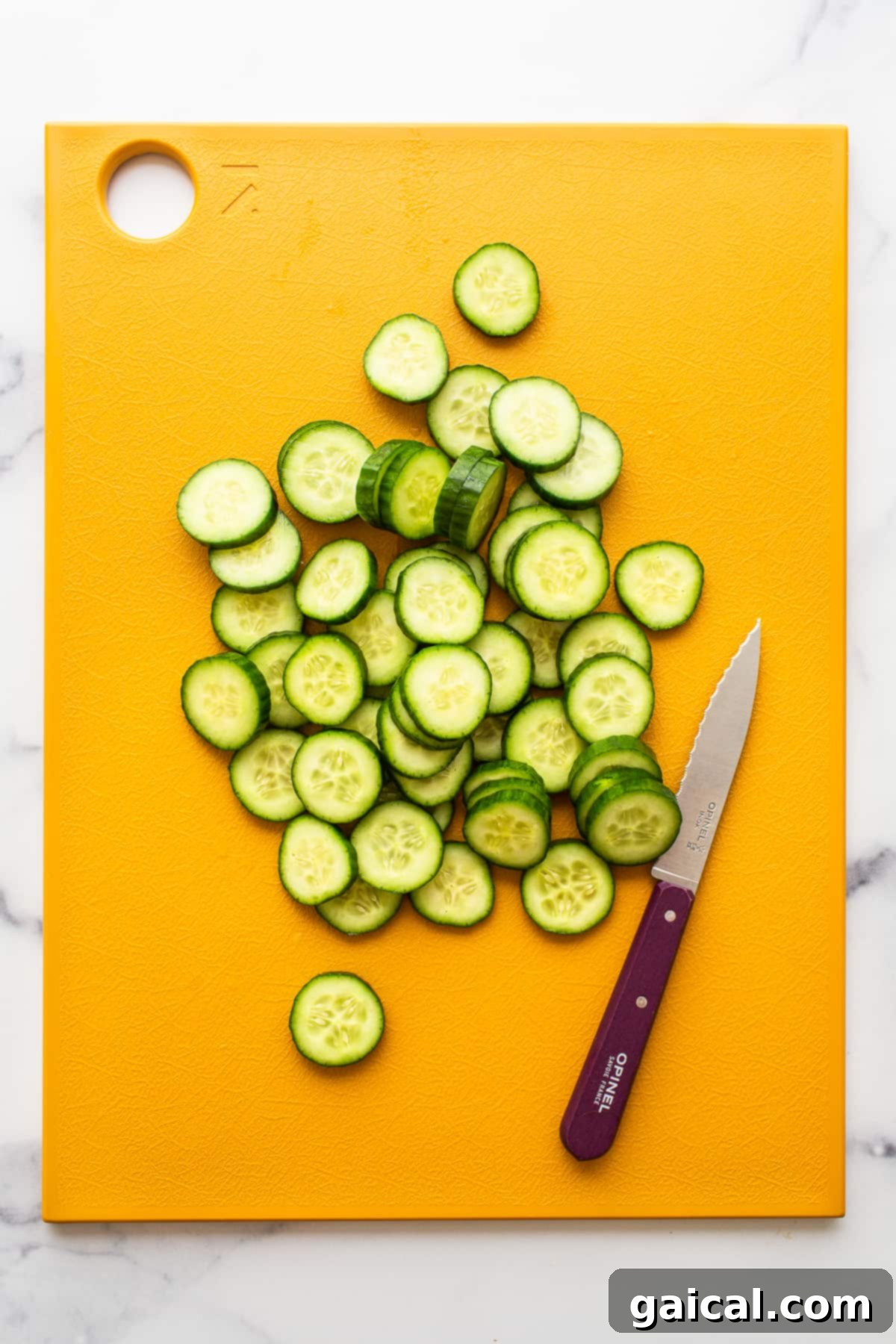 Thinly sliced cucumbers on a cutting board, ready for the salad.