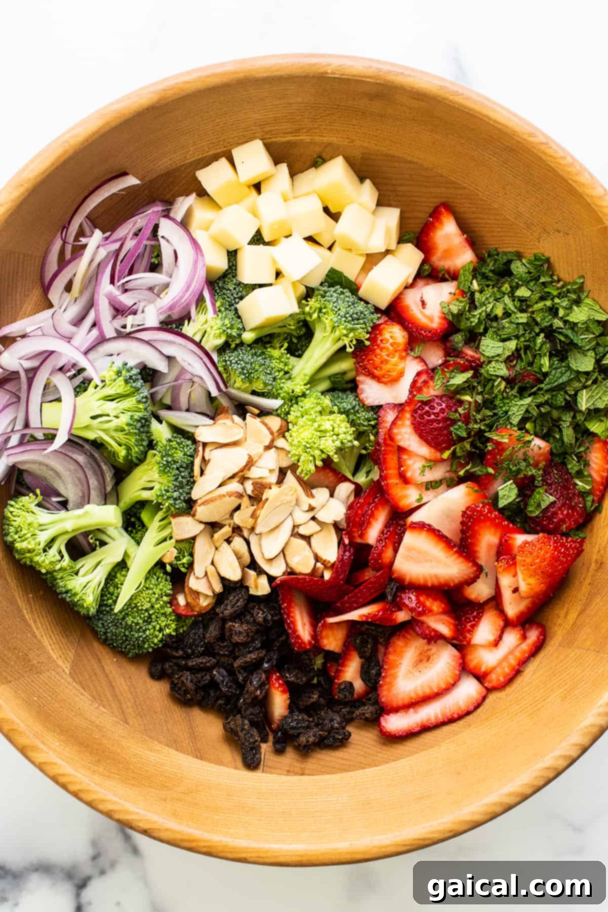 Ready to Toss Strawberry Broccoli Salad Fresh ingredients for strawberry broccoli salad arranged in a large wooden bowl, ready to be dressed.