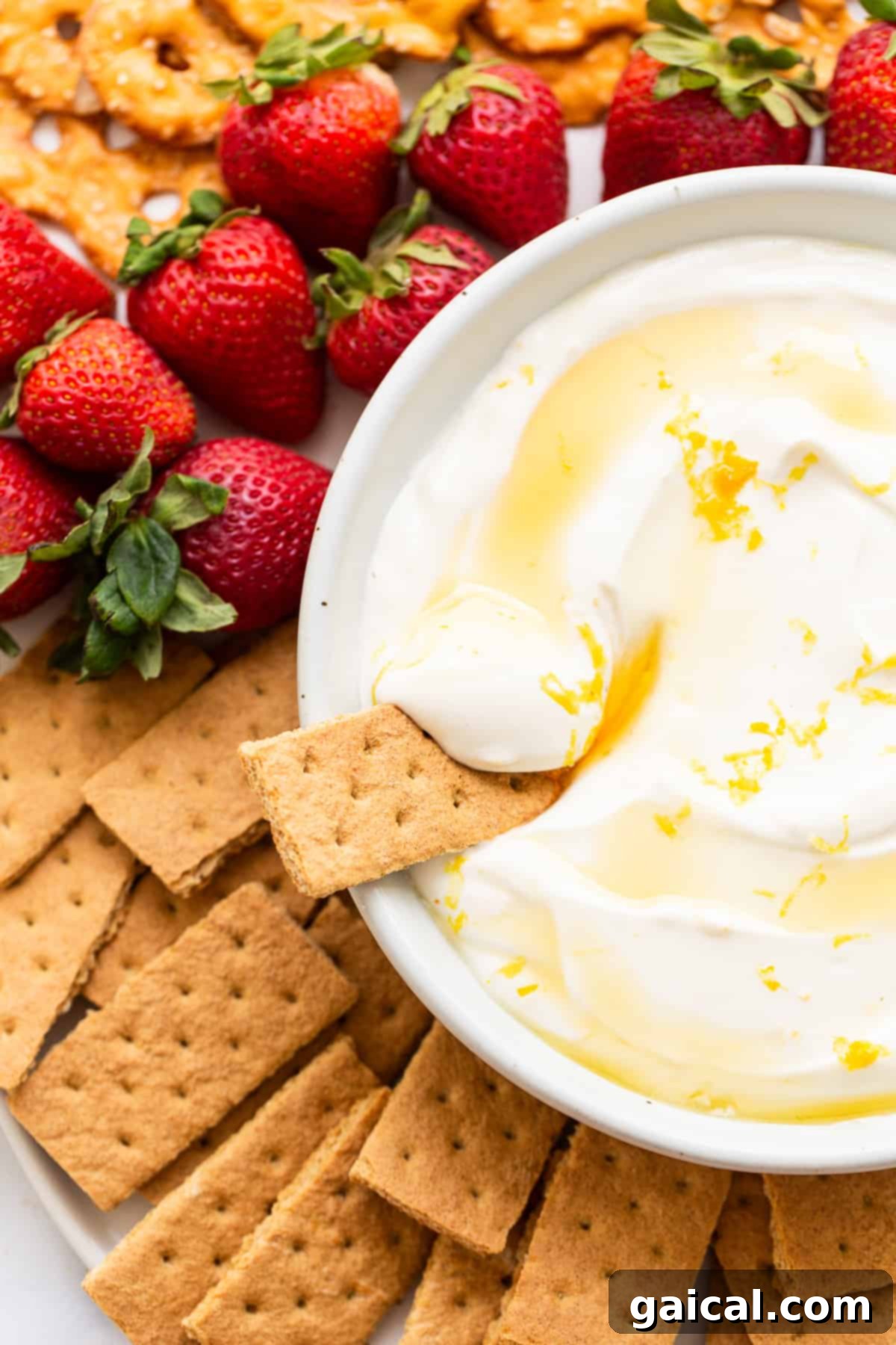 A creamy fruit dip in a bowl, surrounded by fresh strawberries and golden graham crackers, ready for dipping.