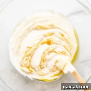 Whipped creamy fruit dip mixture in a bowl with a wooden spoon, showing its smooth texture.