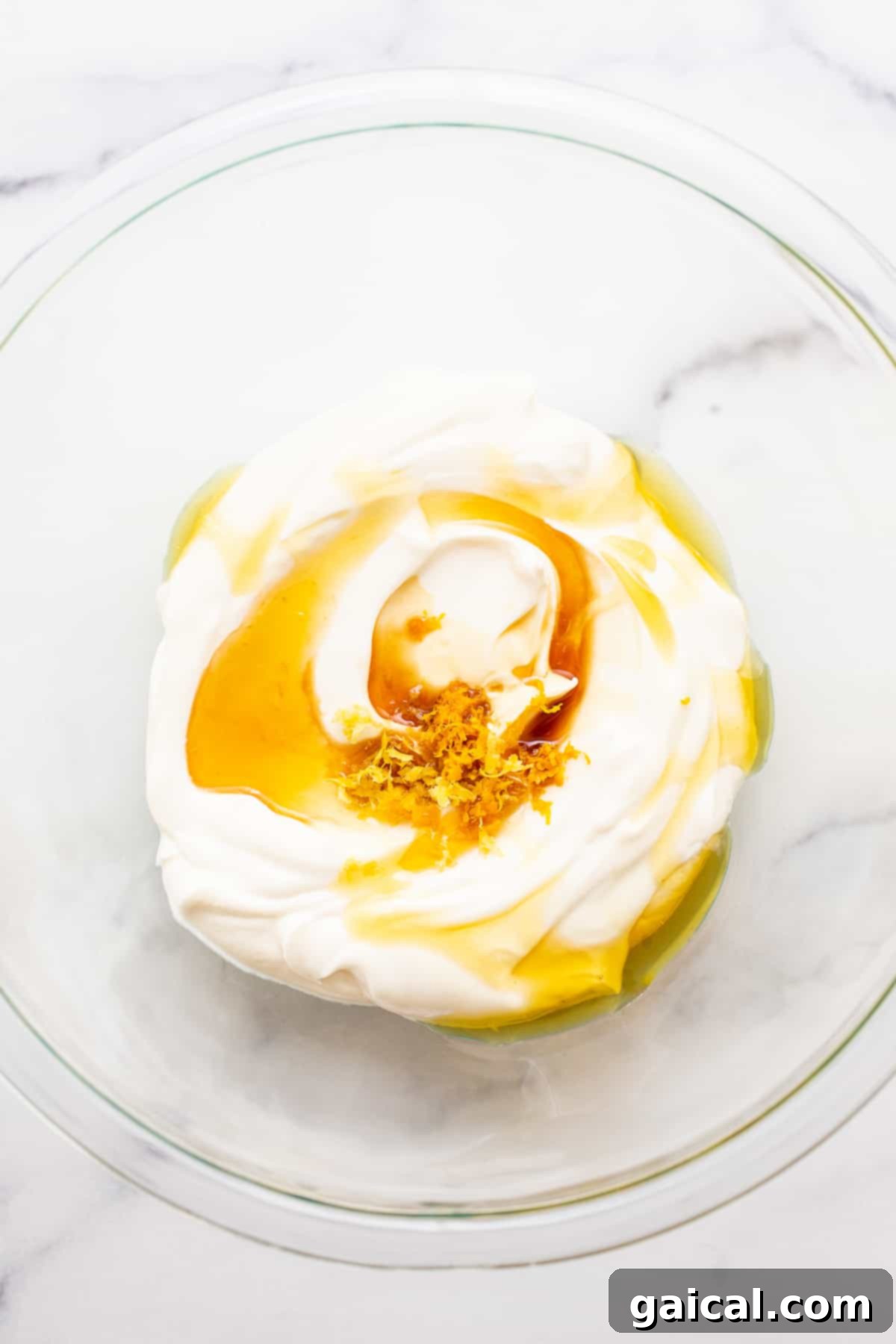 Creamy Greek yogurt glistening in a bowl, infused with golden honey and vibrant lemon zest, waiting to be transformed into a delicious dip.