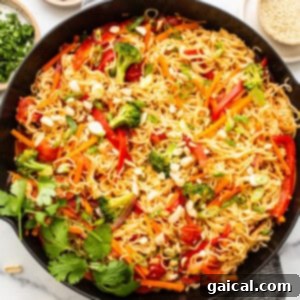 Peanut noodles in cast iron skillet, garnished with fresh herbs.