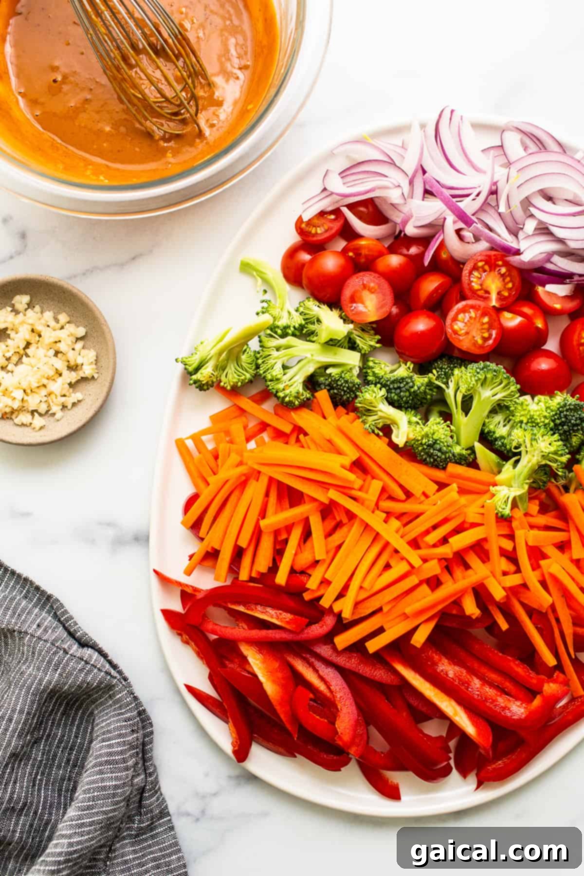 Fresh, Colorful Vegetables for Peanut Noodles A vibrant platter showcasing a colorful assortment of fresh vegetables including carrots, red bell peppers, broccoli florets, cherry tomatoes, and sliced red onion.