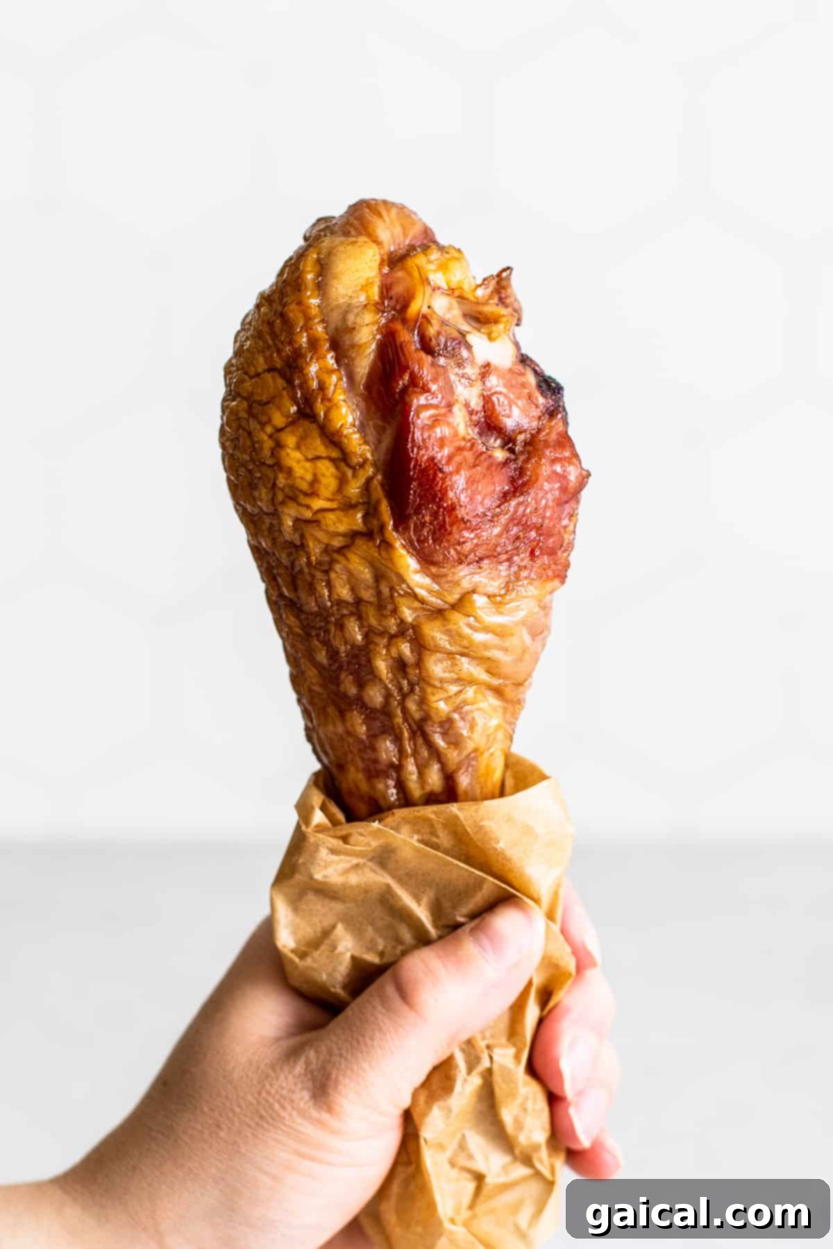 Smoked turkey leg held in a hand, showcasing its golden-brown skin and juicy texture.