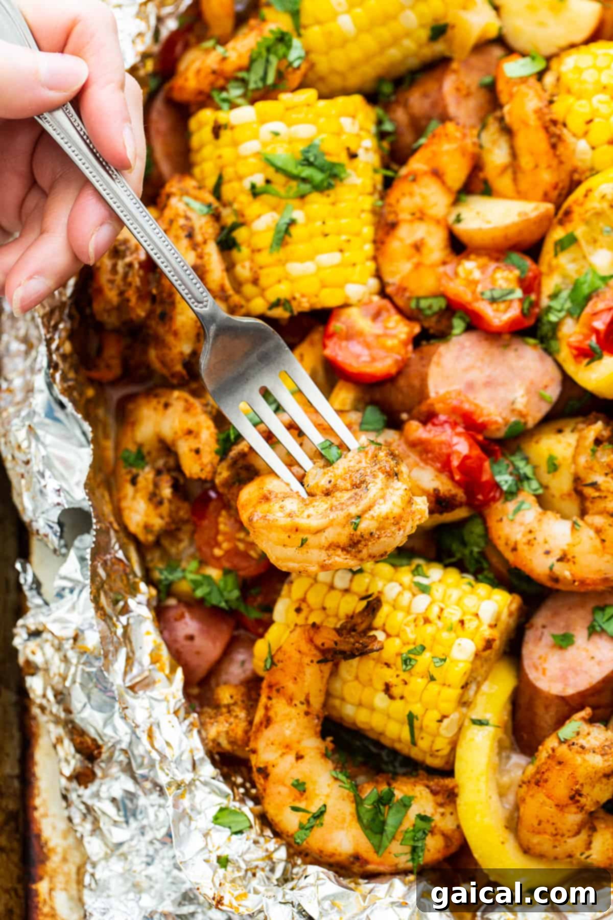 Zesty Shrimp Grill Parcels 7 A fork holding a piece of perfectly cooked shrimp and a corn kernel from a foil packet, ready to eat.