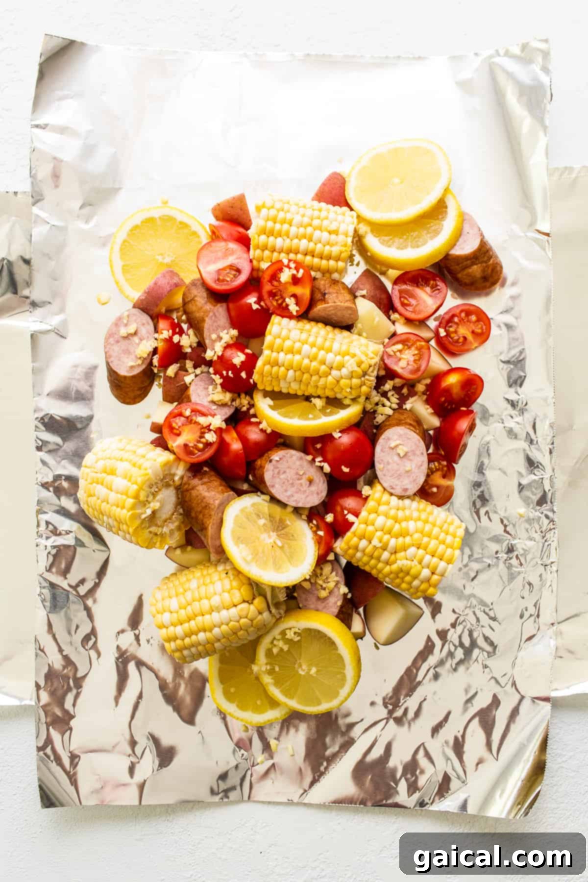 Zesty Shrimp Grill Parcels 3 Raw ingredients, including shrimp, corn, potatoes, and sausage, arranged beautifully in an aluminum foil boat before grilling.