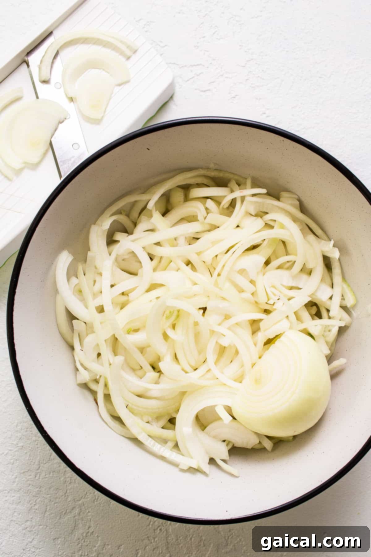 Effortless Caramelized Onions 3 Fresh, whole white onions in a rustic wooden bowl, ready for slicing. Ensuring proper slicing is crucial for successful caramelization.