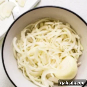 Effortless Caramelized Onions 8 Fresh white onions in a bowl, sliced and ready for cooking.
