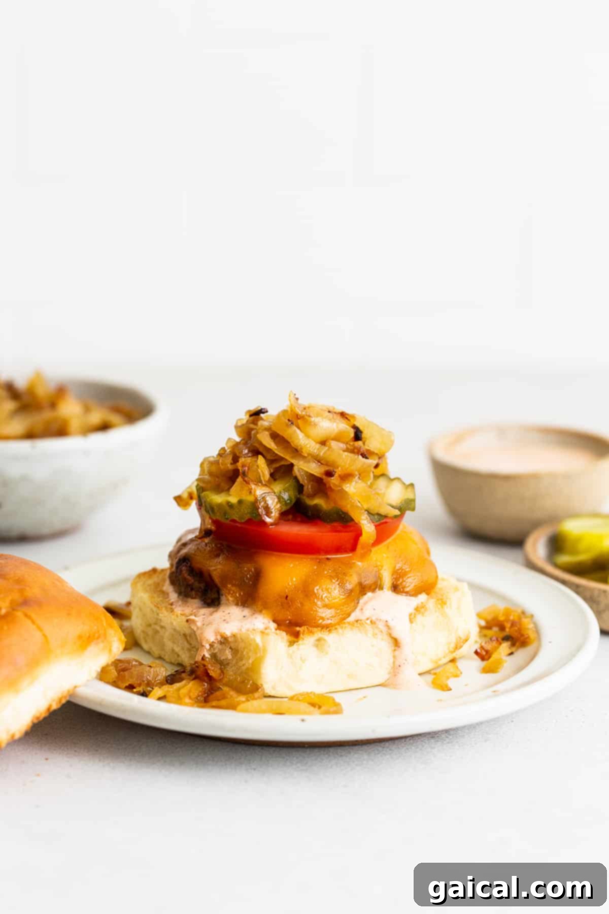 A perfectly cooked homemade burger, piled high with fresh toppings, resting on a plate.