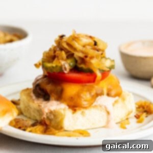 A burger with onions and tomatoes on a plate, ready to be enjoyed.