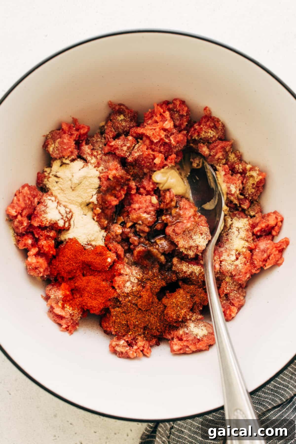A bowl showcasing the fresh ingredients for a homemade burger patty, ready to be mixed.