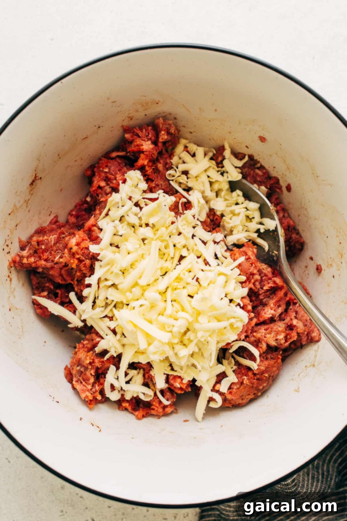 Homemade burger mixture in a bowl, visibly topped with finely grated cold butter.