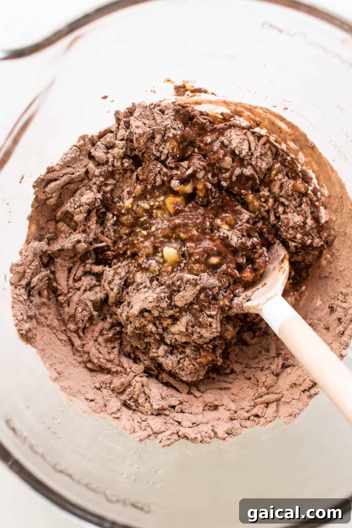Dry and wet ingredients combined in a bowl, forming a rich, chocolatey batter for zucchini bread.