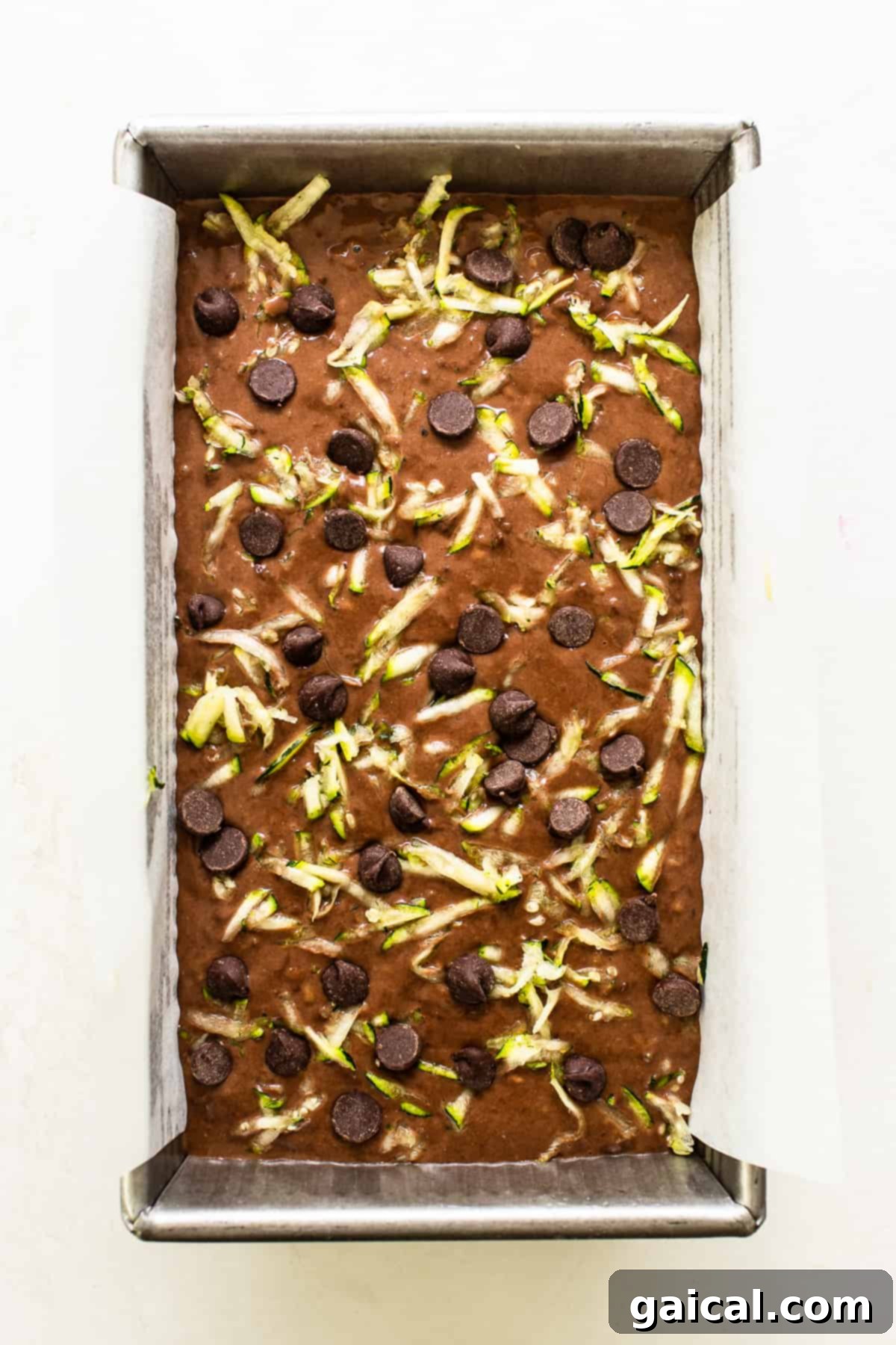 Loaf of chocolate zucchini bread, unbaked, ready to go into the oven with a sprinkle of extra chocolate chips.