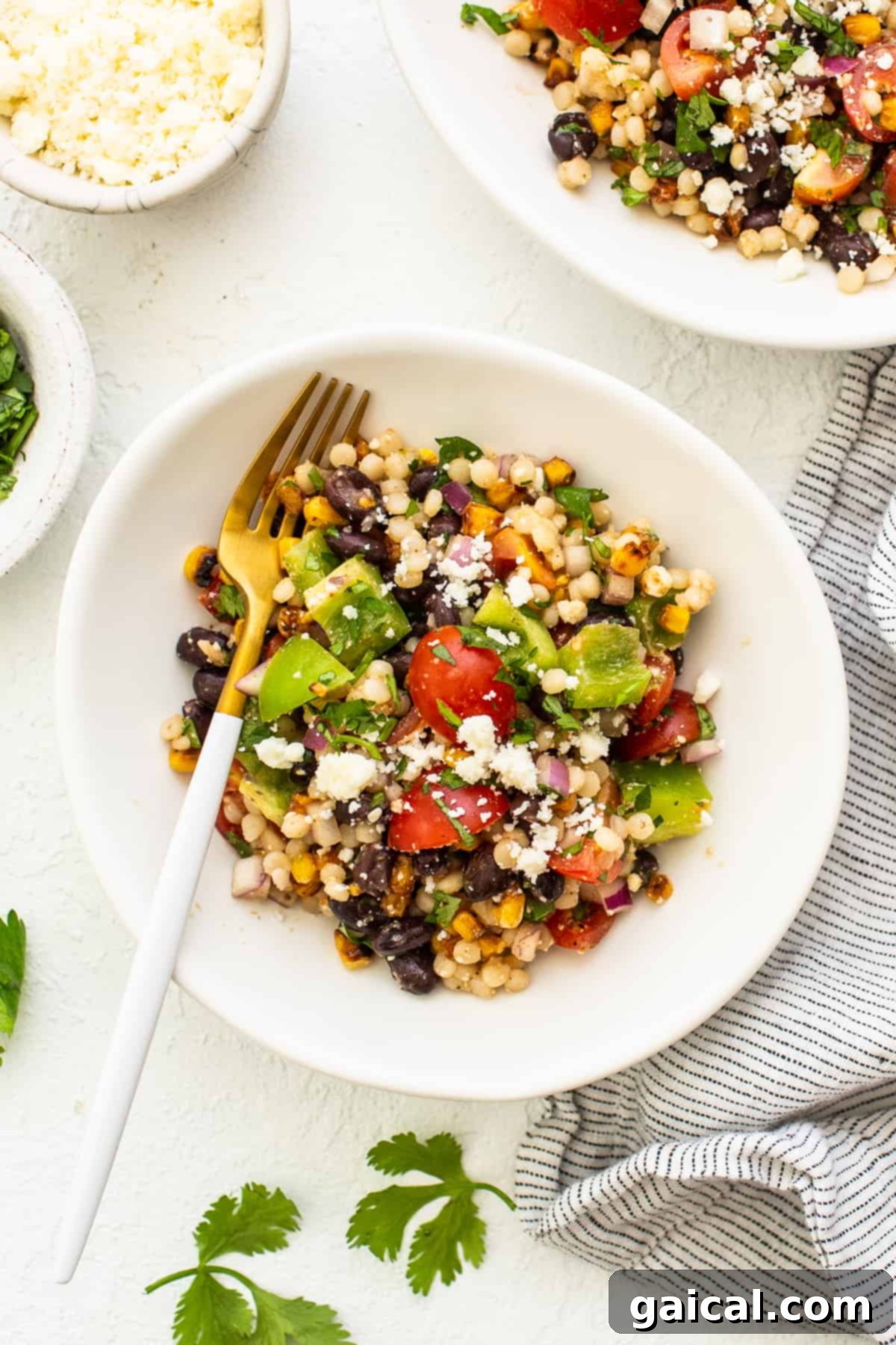 Vibrant Black Bean Couscous Medley 7 A close-up of a serving of black bean couscous salad in a white bowl with a fork, ready to be enjoyed.