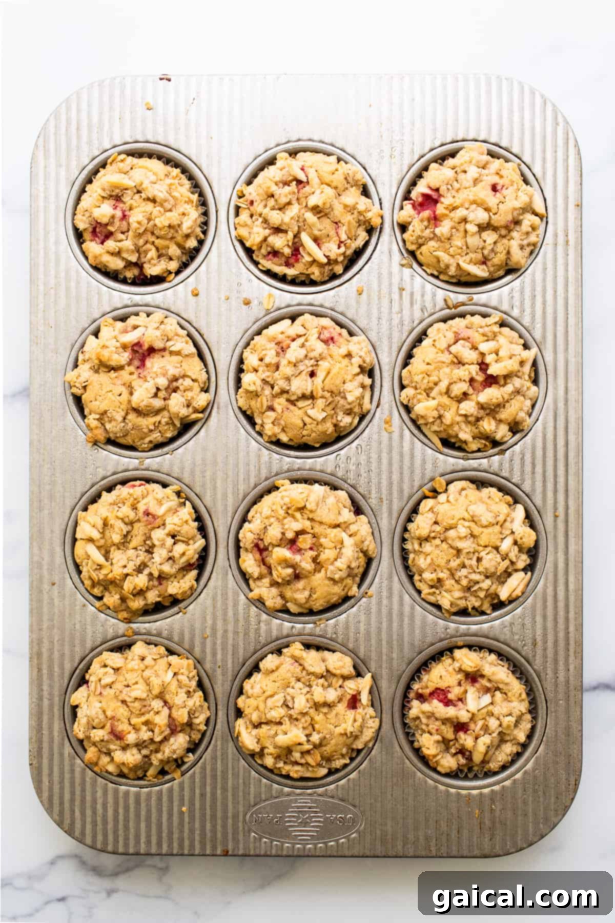 Bursting Raspberry Muffins 6 Freshly baked raspberry muffins cooling in a muffin tin, their golden streusel tops hinting at deliciousness.