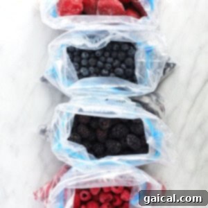Bursting Raspberry Muffins 7 Three bags of various frozen berries (raspberries, blueberries, blackberries) on a kitchen counter, ready for storage.