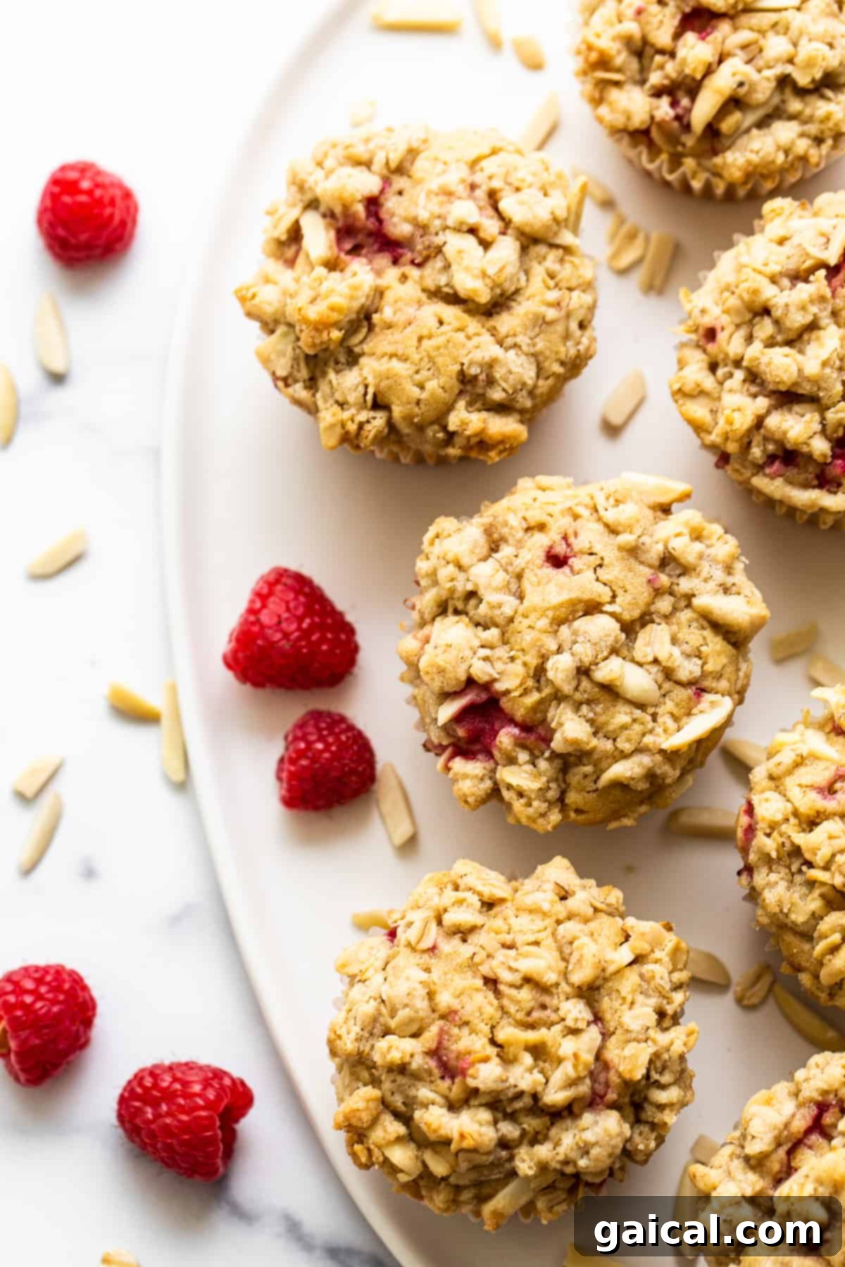 Bursting Raspberry Muffins 8 A stack of golden, streusel-topped raspberry muffins on a plate, ready to be served and enjoyed.