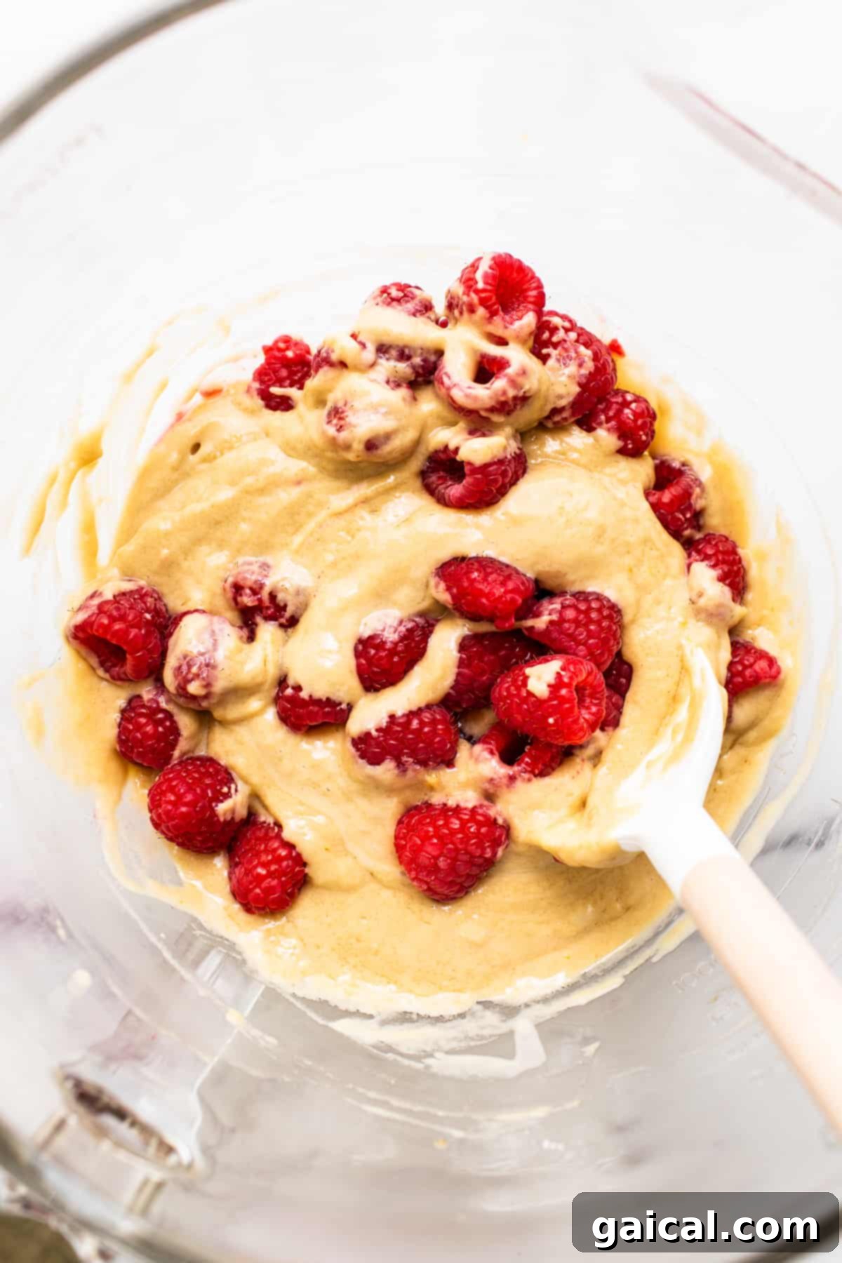 Bursting Raspberry Muffins 5 Thick, vibrant raspberry muffin batter in a mixing bowl, speckled with fresh red raspberries, ready for scooping into a muffin tin.