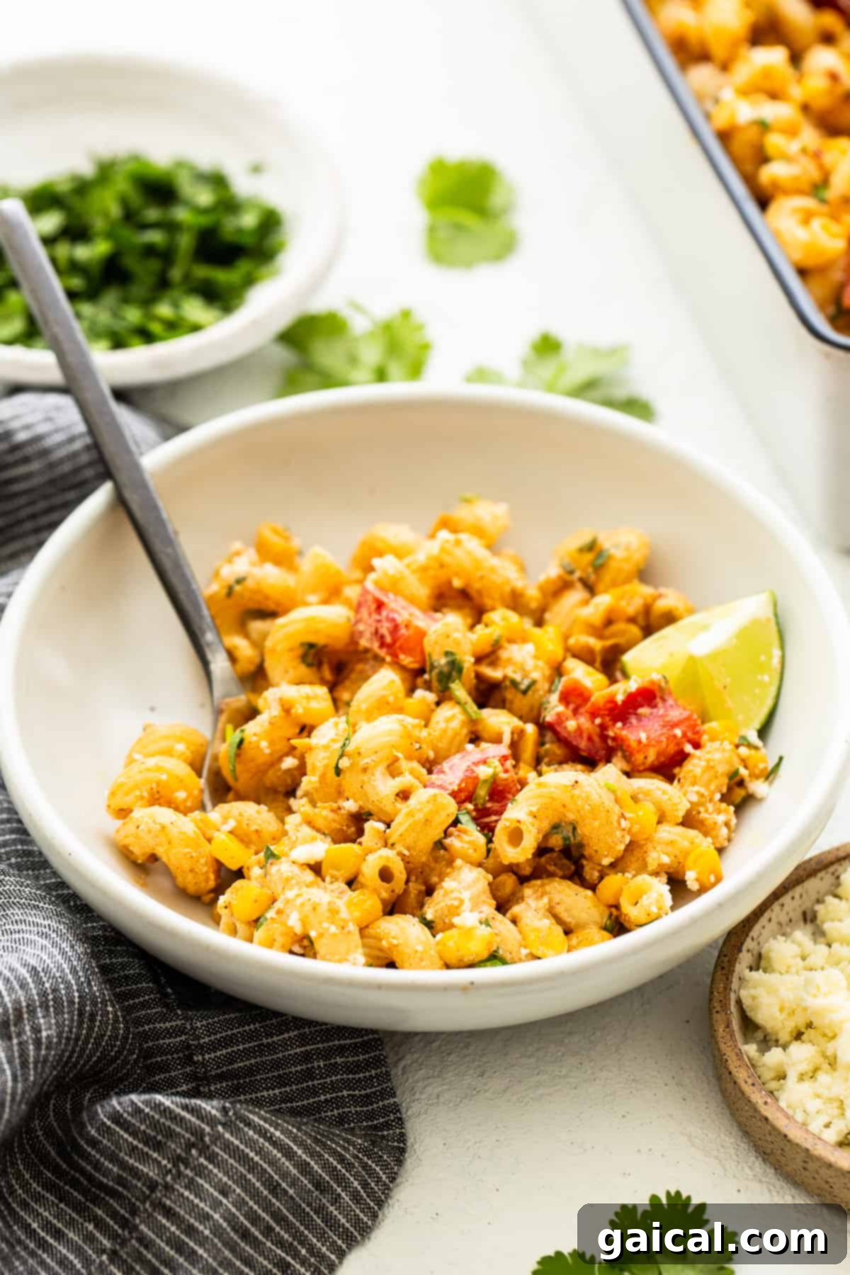 A serving of Mexican Street Corn Pasta Salad in a white bowl, garnished with fresh herbs, ready to be eaten.