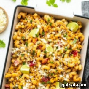 A vibrant Mexican Street Corn Pasta Salad in a serving bowl, garnished with fresh cilantro and lime wedges.