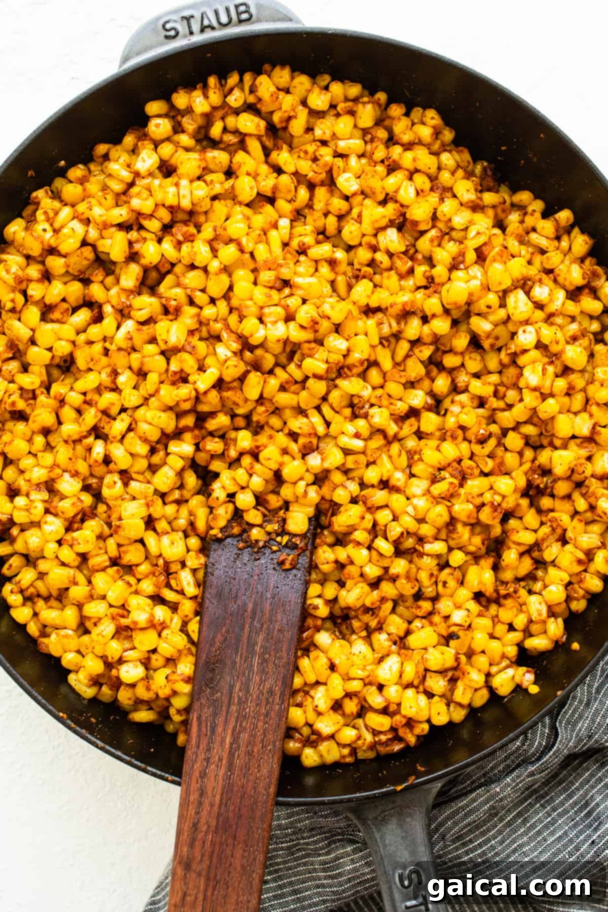 Fresh corn kernels cooking in a cast iron skillet, lightly browned and seasoned.