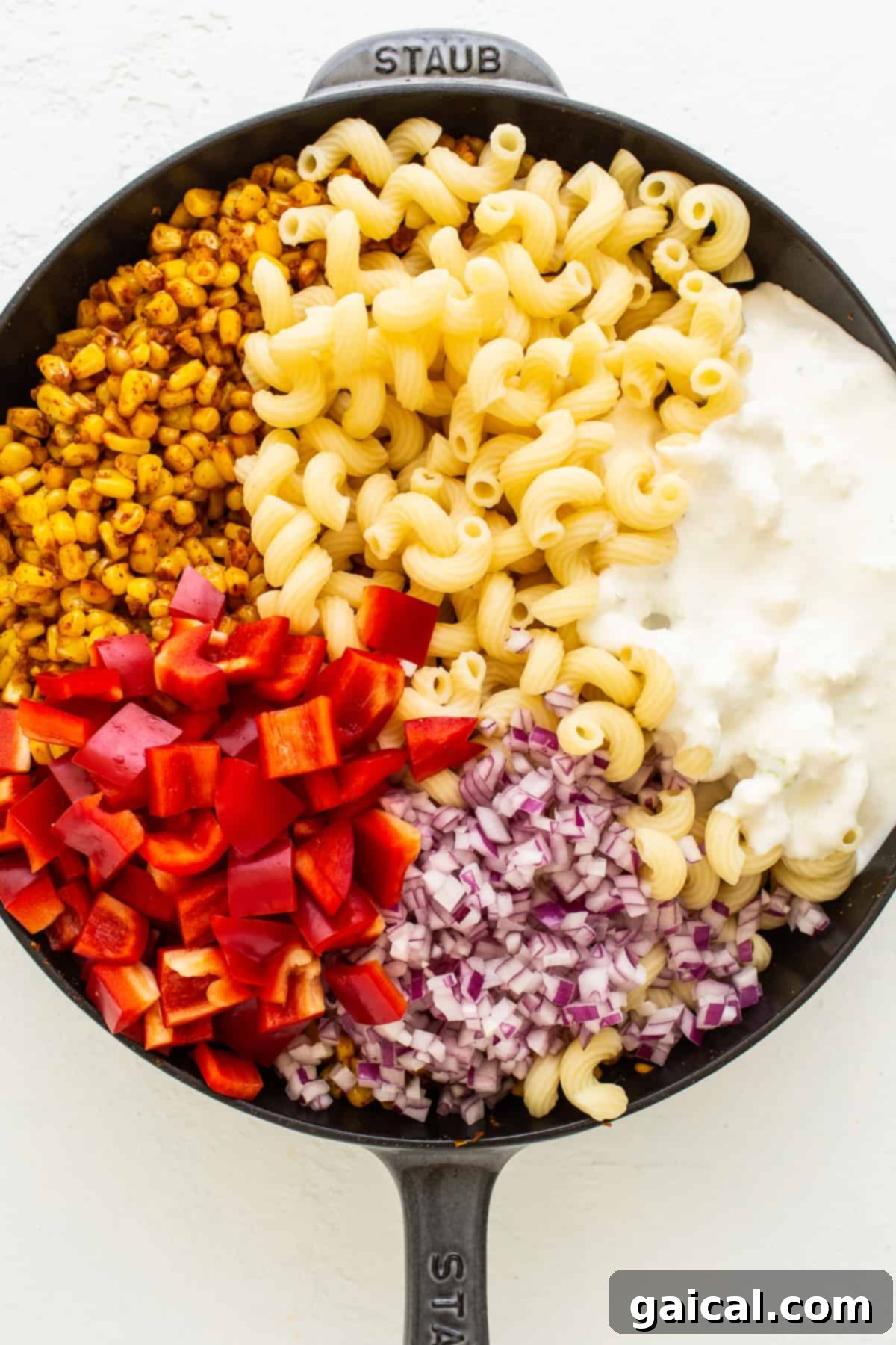 Close-up of corn, garlic, and spices cooking in a cast iron skillet, creating a rich aroma.