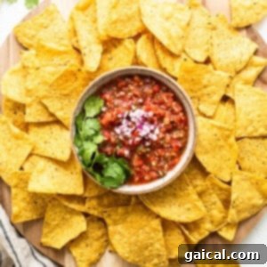 Nachos with fresh salsa on a wooden cutting board, ready to eat.