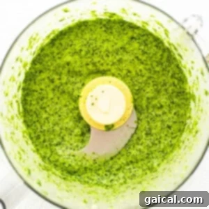Vibrant Herb Dressing 4 Green sauce in a food processor, mid-blend, showing the vibrant color of the herbs.