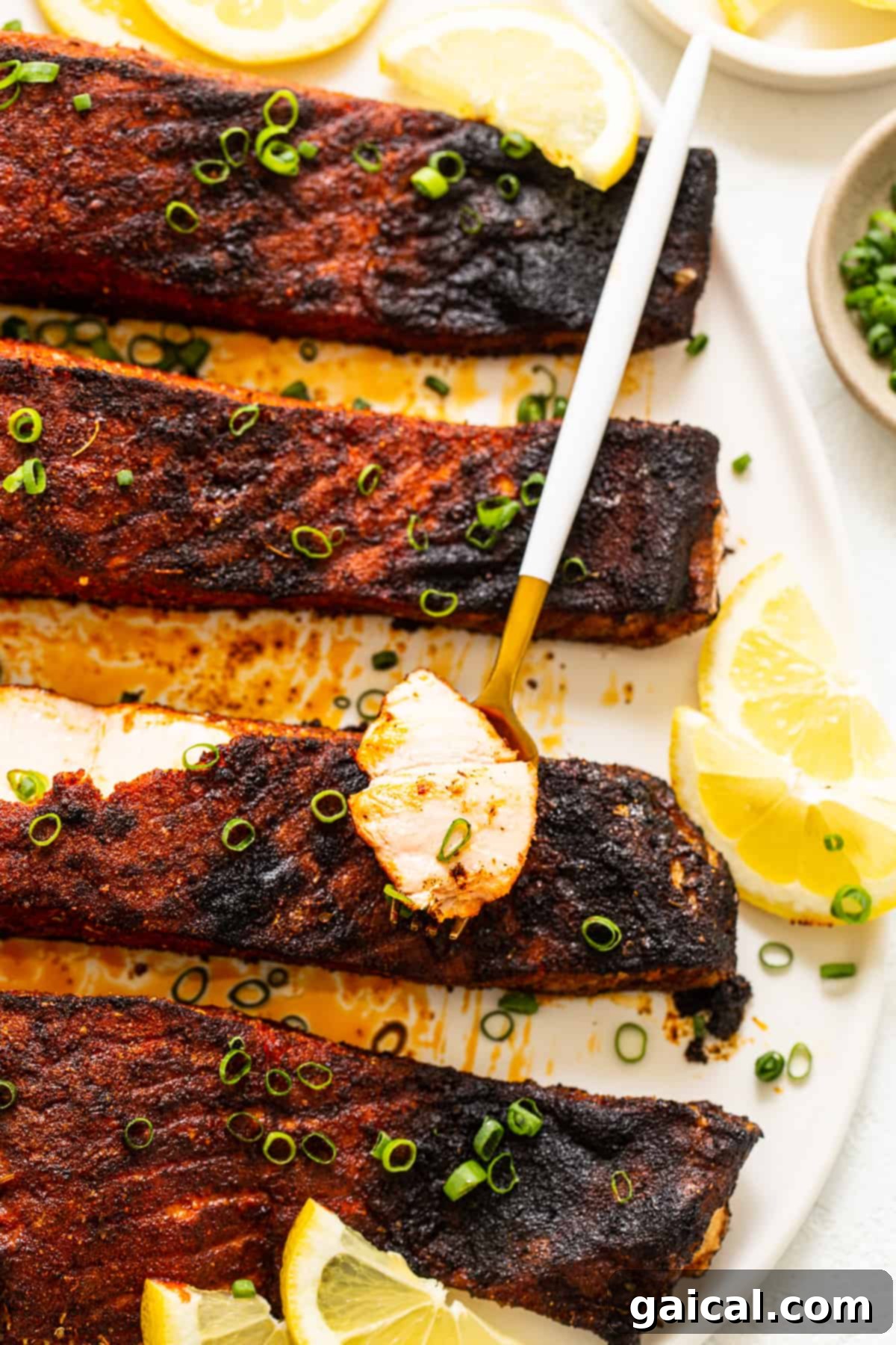 Cajun-Spiced Salmon Fillet 7 A perfectly broiled blackened salmon fillet, garnished with vibrant green onions and fresh lemon wedges, ready for serving.