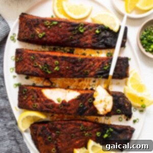 Cajun-Spiced Salmon Fillet 12 Blackened salmon fillets on a plate with fresh lemon wedges, ready to be served, highlighting the vibrant color contrast.